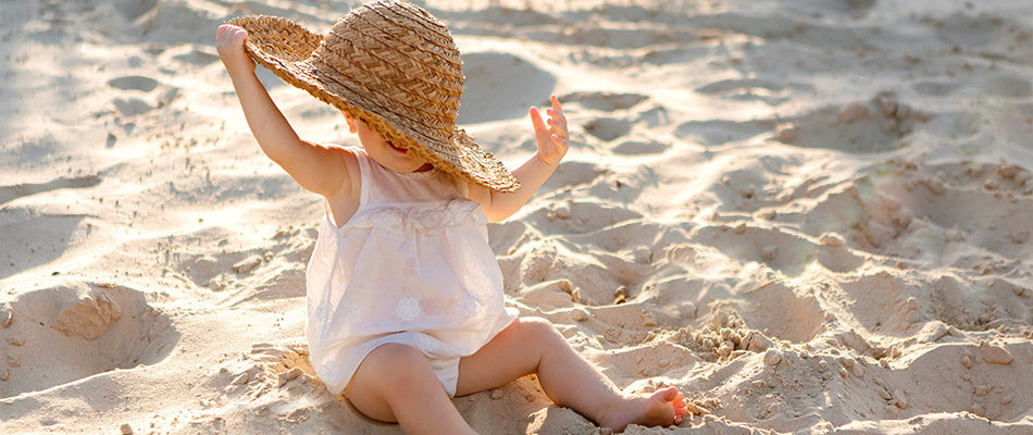 toddler in big hat on the beach