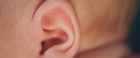  A close-up view of a baby's ear, highlighting the delicate details and natural light pink hue.